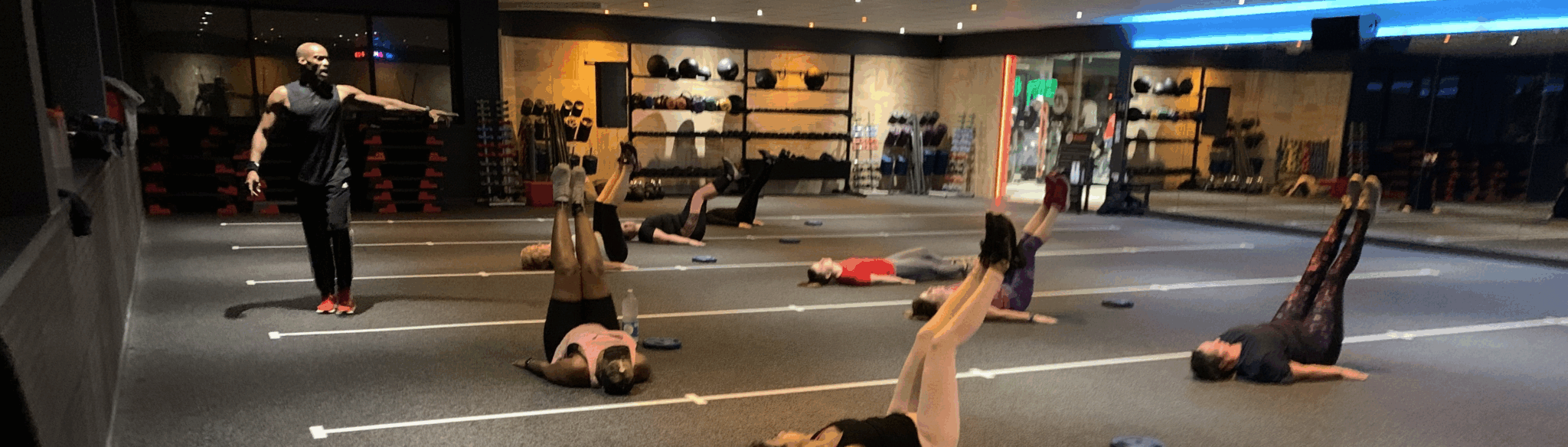 Fitness instructor guiding a group workout in a gym.