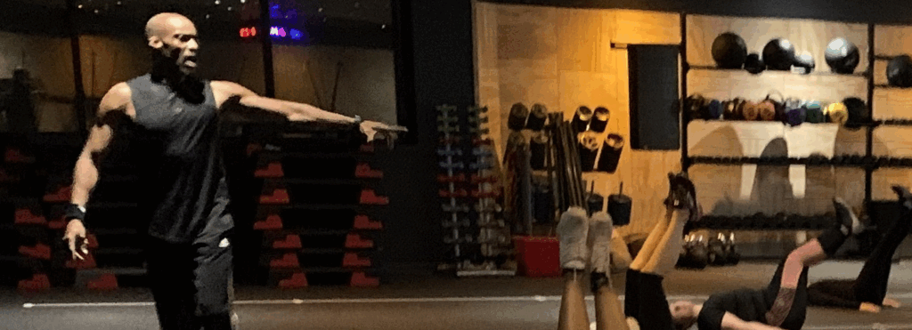Fitness instructor guiding a group workout in a gym.